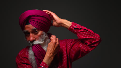 Close-Up-Low-Key-Studio-Lighting-Shot-Of-Senior-Sikh-Man-With-Beard-Using-Salai-Needle-When-Putting-On-Turban-Against-Dark-Background-Shot-In-Real-Time-2